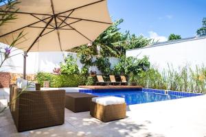 圣若昂-德雷玉兰别墅旅馆的一个带遮阳伞和椅子的庭院和一个游泳池