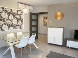 莱里达Apartamentos Real Lleida的一间设有玻璃桌和白色椅子的用餐室