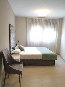 莱里达Apartamentos Real Lleida的卧室配有床、椅子和窗户。