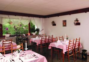 Bad Endbach伯克旅馆的用餐室配有桌椅和粉红色的桌布