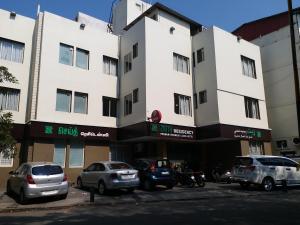 钦奈Zaith Residency Near US Consulate & Apollo hospitals的白色的建筑,有汽车停在停车场