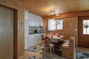 SattelFerienwohnung Sunnehöckli的厨房配有白色橱柜和桌椅