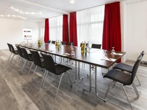 汉诺威DORMERO Hotel Hannover-Langenhagen Airport的大型会议室,配有长桌子和椅子