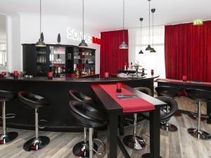 汉诺威DORMERO Hotel Hannover-Langenhagen Airport的酒吧,设有黑凳子和红色桌子