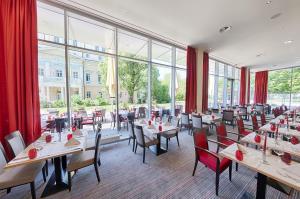 达姆施塔特Welcome Hotel Darmstadt City Center的餐厅设有桌椅和大窗户。