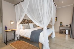 侯斯普瑞特尼亚莱提旅馆的卧室配有带白色窗帘的天蓬床