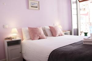 科英布拉库布拉鲁斯酒店的卧室配有带粉红色枕头的大型白色床