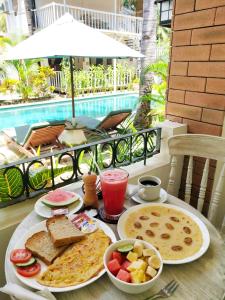 吉利特拉旺安White Coconut Resort的餐桌,在游泳池前的桌子上摆上早餐