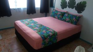 AmuriAitutaki Budget Accommodation的一间卧室配有一张带粉色床单和鲜花的床。