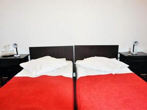 克利默内什蒂Hotel Central的卧室配有红色和白色的床和两张桌子