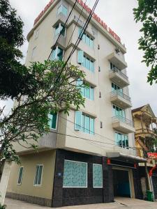 荣市Hoang Ngan 1 Hotel - TP. Vinh的一座高大的白色建筑,有很多窗户