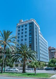瓦伦西亚瓦伦西亚中心酒店的一座高大的建筑,前面有棕榈树