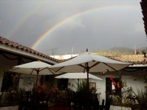 GüicánHotel Casa del Colibri的天上一带雨伞的房子上的彩虹