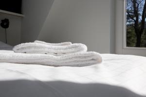 哈尔德伦博克别墅公园酒店的三条毛巾堆在白色床的顶部