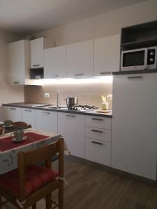 莱维科特尔梅Appartamento Verdebleu - Lago e Terme的厨房配有白色橱柜和炉灶烤箱。