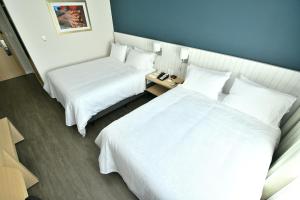 亚松森Holiday Inn Express Asuncion Aviadores , an IHG Hotel的配有白色床单的酒店客房内的两张床