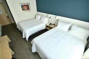 亚松森Holiday Inn Express Asuncion Aviadores , an IHG Hotel的配有白色床单的酒店客房内的两张床
