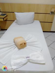 容迪亚伊Hotel Central Rosário的白色的床,上面有白色衬衫和帽子