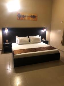 伊凯贾Posh Apartments Business Hotel的一间卧室配有一张带两个灯的大床