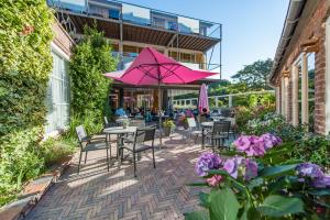 佐特兰德夏日欲望花园酒店的一个带桌椅和粉红色遮阳伞的庭院。