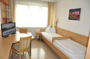 林茨科尔平林茨旅舍的酒店客房设有两张床、一张桌子和一台电视。
