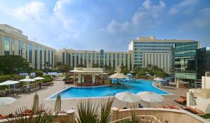 迪拜Millennium Airport Hotel Dubai的一个带遮阳伞的大型游泳池和酒店