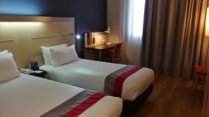 马拉加Holiday Inn Express Málaga Airport, an IHG Hotel的酒店客房设有两张床和一张桌子。