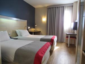 马拉加Holiday Inn Express Málaga Airport, an IHG Hotel的酒店客房设有两张床和电视。
