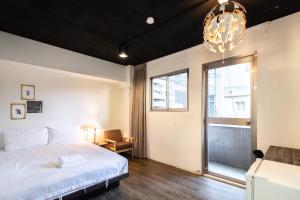 台北Place Inn Taipei的一间卧室设有一张床、一个窗户和一个吊灯。