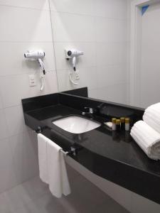 因达亚尔Tri Hotel Executive Indaial的浴室配有带水槽和毛巾的黑色台面。