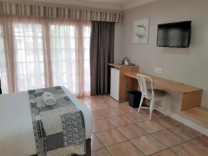 弗莱海德Shonalanga Lodge的客房设有床、书桌和电视。