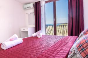 普罗马尼亚Apartments Family Roso的一间卧室配有带毛巾的粉红色床和阳台