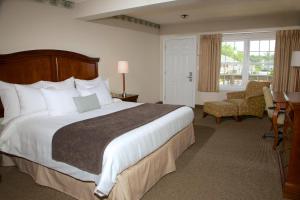 丹尼斯港希尔假日套房酒店的酒店客房带一张大床和一把椅子