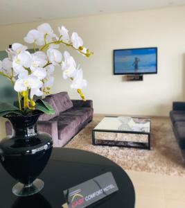 ParanaíbaCast Comfort Hotel的客厅里一张带白色花朵的黑色花瓶