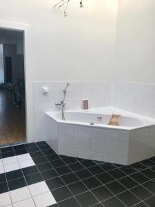 吕伐登GUESTHOUSE UIT DE KUNST的浴室铺有黑色瓷砖地板,配有白色浴缸。