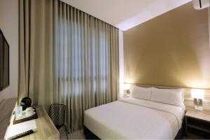 伊洛伊洛Figtree Hotel的配有一张床、一张书桌和一扇窗户的酒店客房