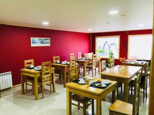 纳塔列斯港Hostal Andes Patagonicos的餐厅设有木桌、椅子和红色的墙壁