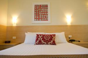 沃加沃加俱乐部汽车旅馆和公寓的一间卧室配有一张红色枕头的床