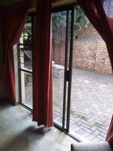 米德尔堡Woodpecker Guesthouse Middelburg Mpumalanga的外面有一只猫和一只开放式滑动玻璃门