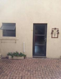 米德尔堡Woodpecker Guesthouse Middelburg Mpumalanga的通往有窗户和盆栽的建筑物的门