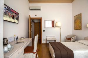 锡耶纳帕拉迪索广场住宿旅馆的酒店客房带一张床铺、一张书桌和一间卧室