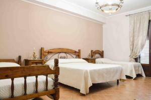 MontelepreHotel Castello di Giuliano的一间卧室配有三张床和吊灯。