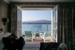 温德米尔低木湾酒店的卧室设有大型滑动玻璃门、桌子和椅子
