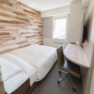 钏路Super Hotel Kushiro Natural Hot Spring的一间卧室设有木墙和一张书桌