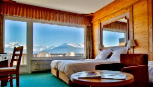 克莱恩 蒙塔纳Hotel-Restaurant Le Mont Paisible, Crans-Montana的酒店客房设有床、桌子和窗户。