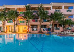 卡拉马孔Caretta Beach Resort & WaterPark的棕榈树建筑前的游泳池