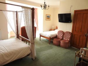 巴茅思Môr Wyn Guest House的一间卧室设有两张床、一台电视和一把椅子