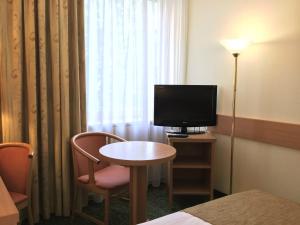 布达佩斯Danubius Hotel Erzsébet City Center的酒店客房配有电视、桌子和椅子