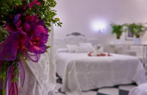 GussagoGiada的白色的客房配有一张带紫色花卉的桌子