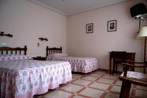 孔苏埃格拉Hostal San Poul的一间卧室配有两张床和一张桌子及椅子